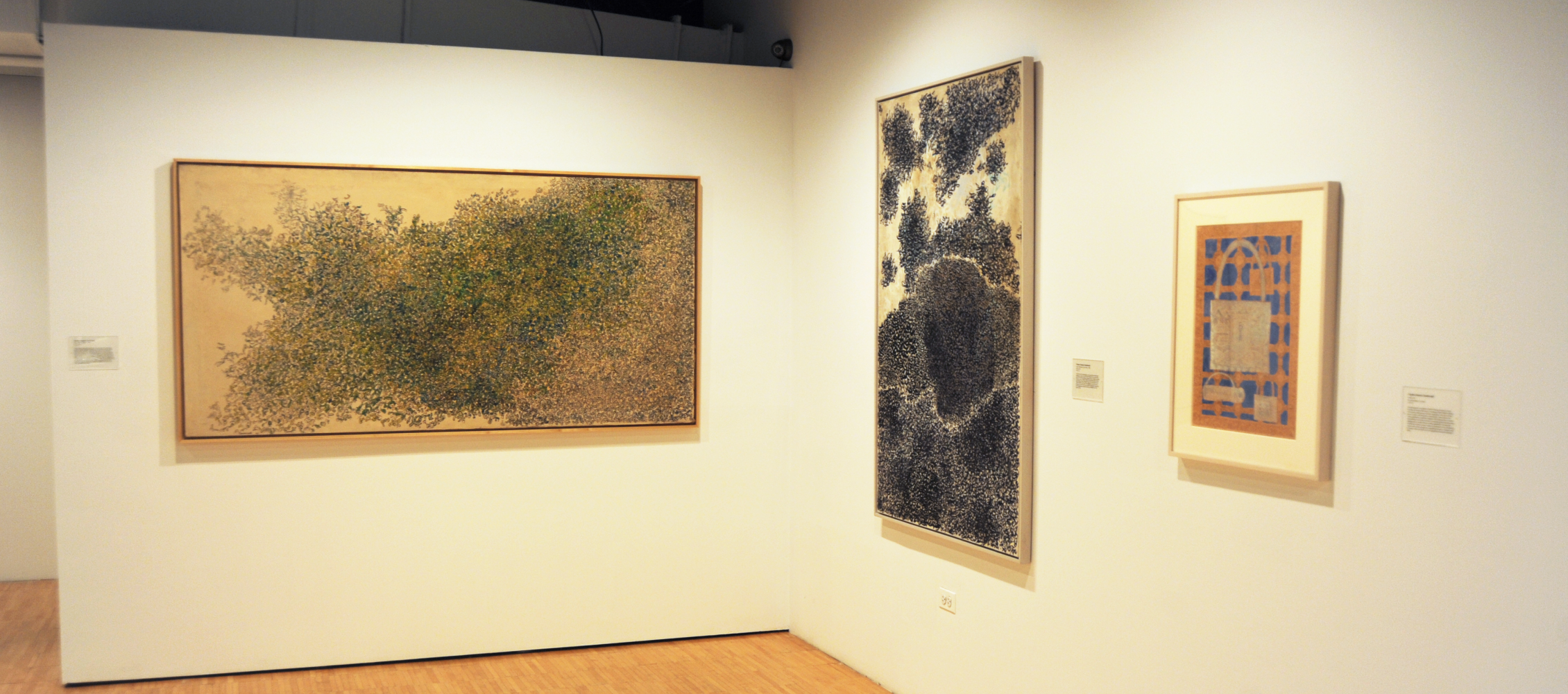 An art gallery interior with framed paintings hung on white wall.