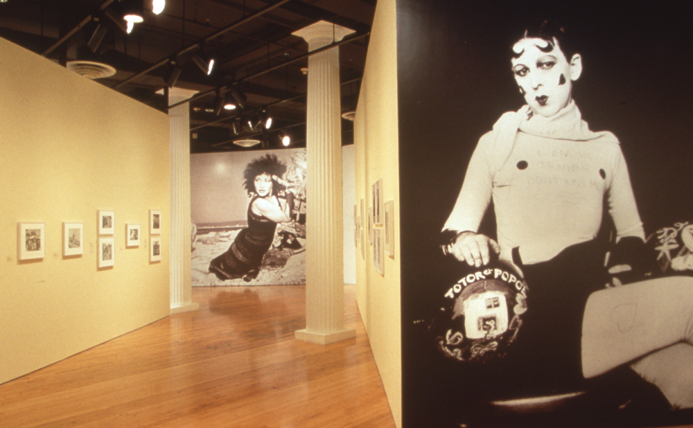 Art gallery interior with framed photos on walls and large monochromatic images in the foreground and background. Alt-text generated by AI.
