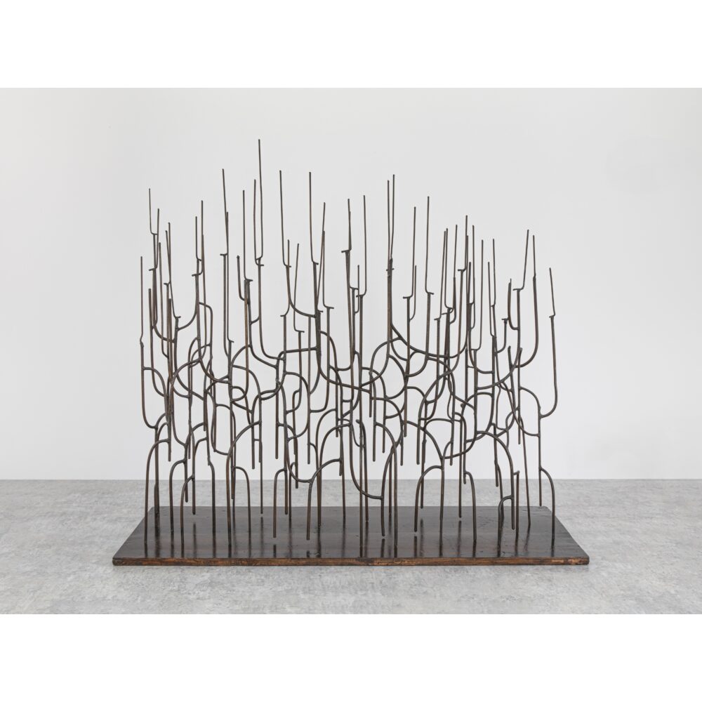 Abstract metal sculpture with interconnected vertical rods on a rectangular base.