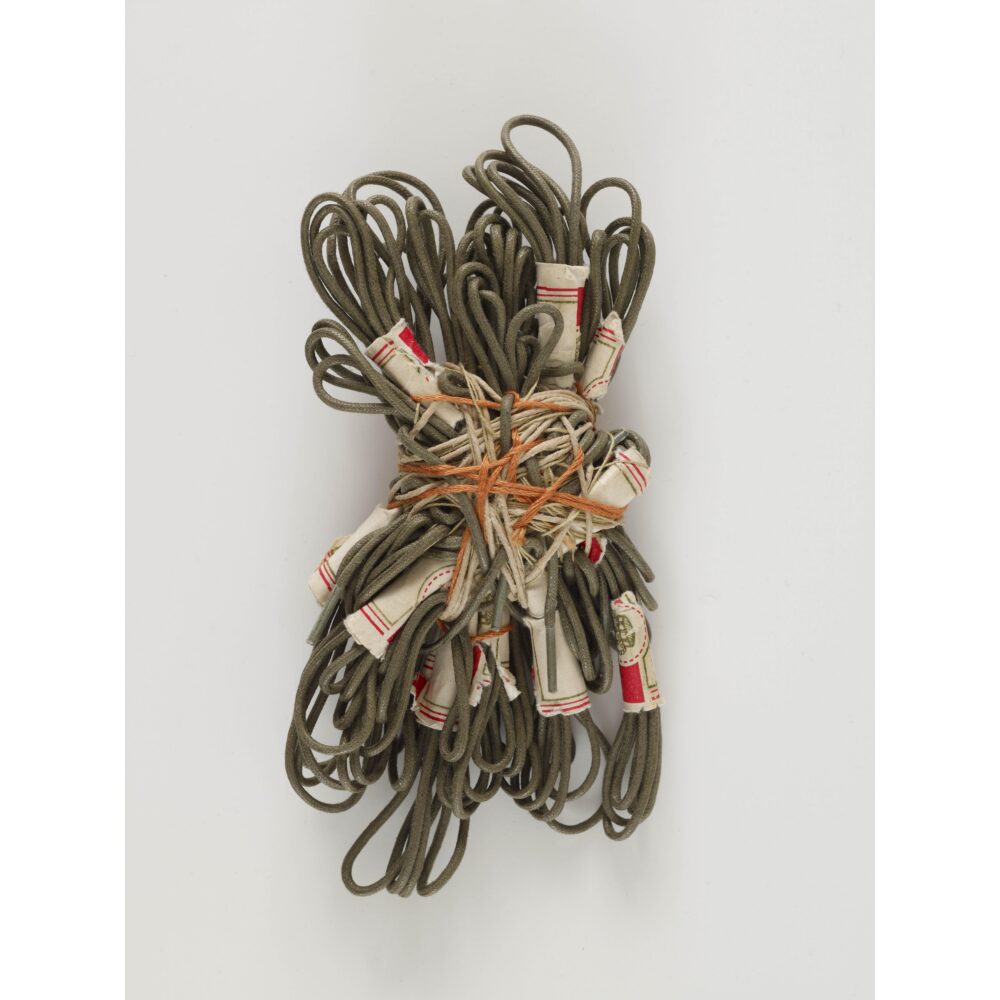 A bundle of olive-green leather cords wrapped with orange string, silk, and paper.