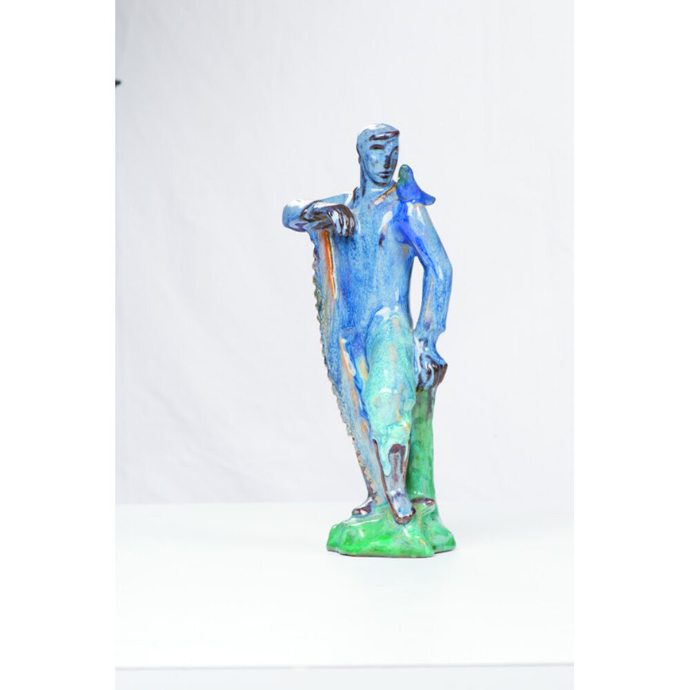 Blue-glazed ceramic figure sculpture of a standing pioneer figure set against a white backdrop. (Alt-text generated by AI)
