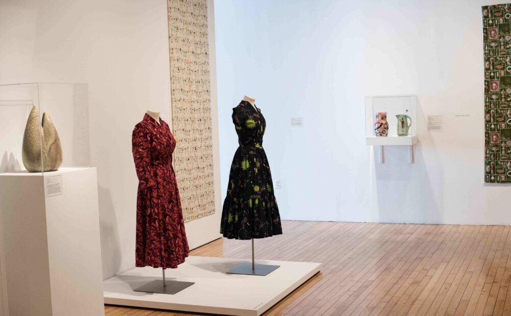 Perspective view of the dress display platform alongside a pedestal-mounted ceramic sculpture in the gallery space. (Alt-text generated by AI)