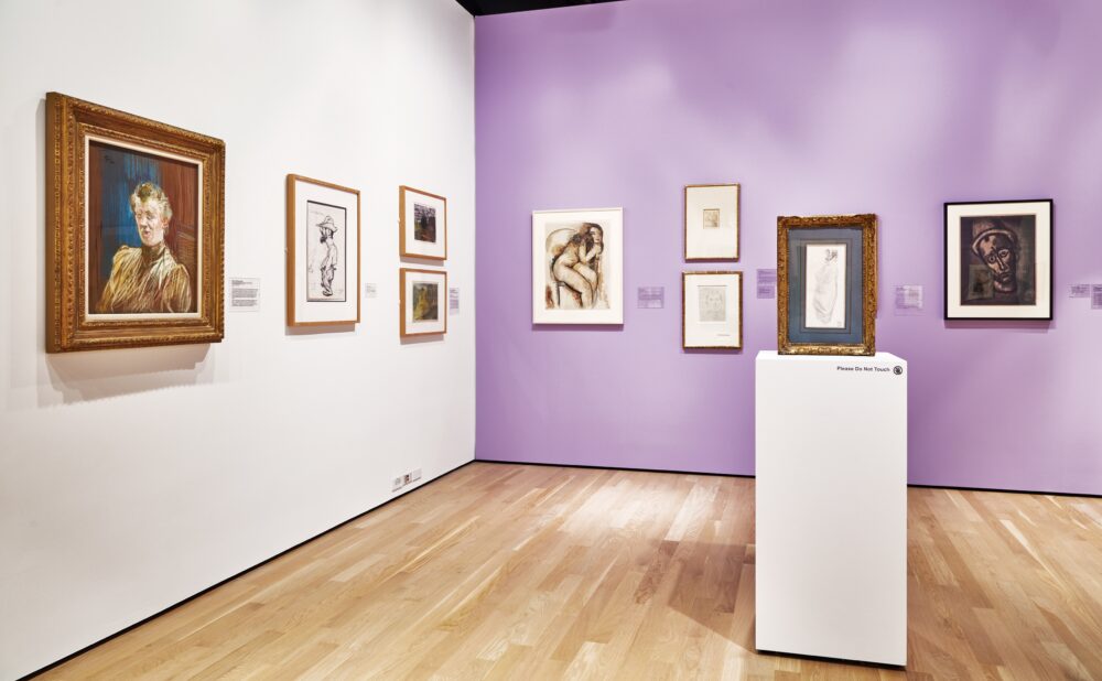 Art gallery with framed artworks on white and lavender walls, featuring paintings, sketches, and a central pedestal display.