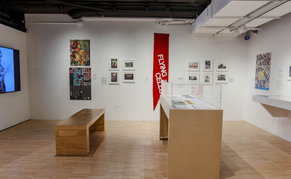 Exhibition room featuring wooden display cases, benches, and red promotional banners hanging from the ceiling. (Alt-text generated by AI)