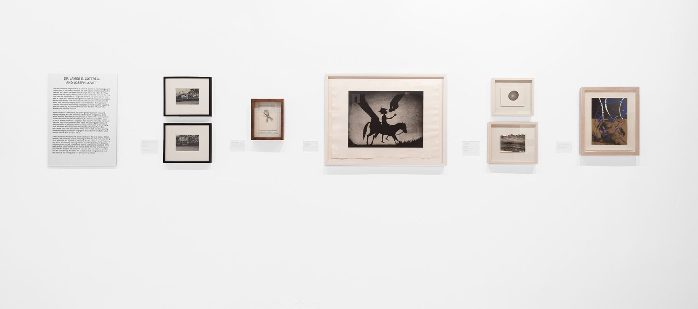 A gallery wall displaying various framed artworks and a text panel.