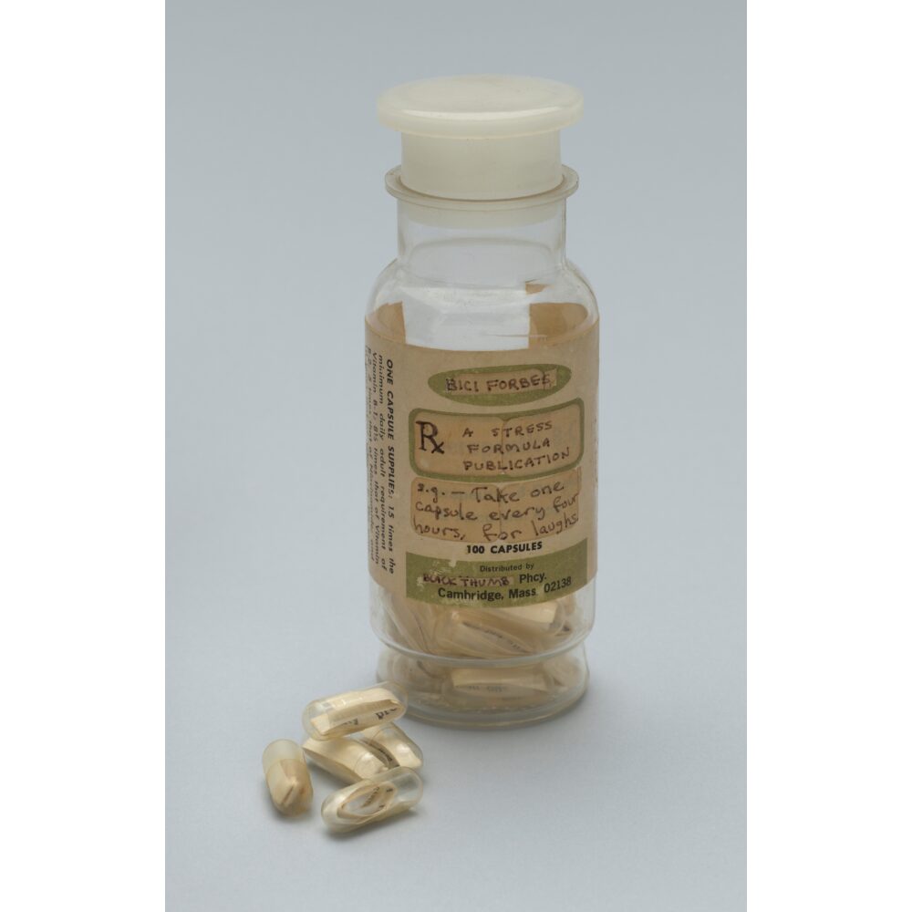 A clear glass apothecary jar filled with capsules, sitting next to a small pile of loose white capsules.  Alt text generated by AI.