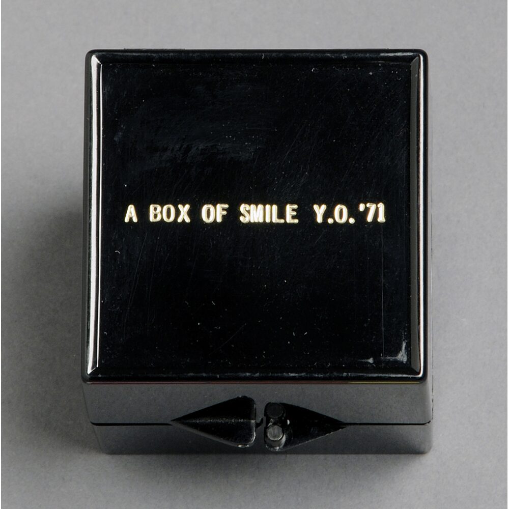 A black cube box resting on a light surface with gold text stamped on the front. Alt text generated by AI.