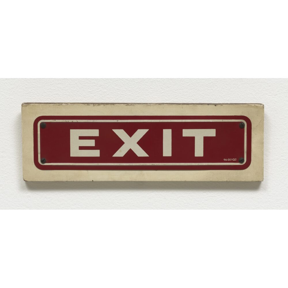 A rectangular cream and red sign displaying the word "EXIT" in bold uppercase letters. Alt text generated by AI.