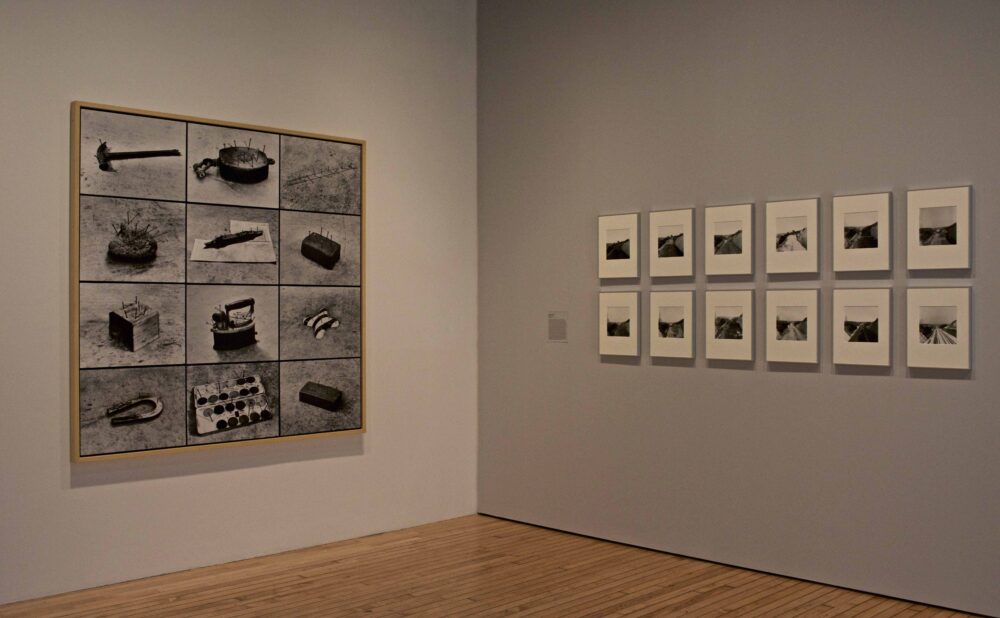 Corner gallery view featuring a multi-panel grid photograph on the left wall and a grid of fifteen framed small prints on the right wall. (Alt-text generated by AI)