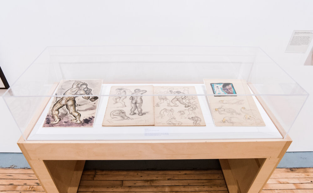 Acrylic display case showcasing archival sketches laid flat. (Alt-text generated by AI)