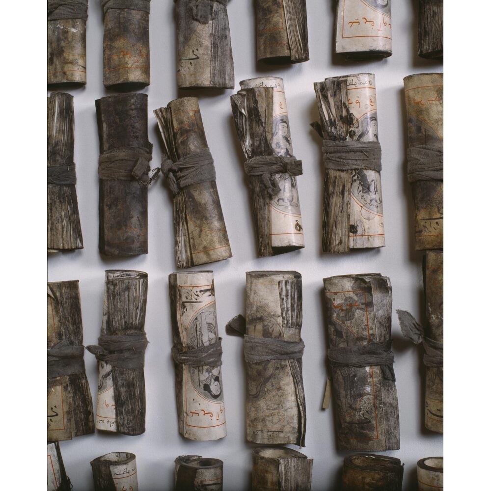 Close-up detail of small canvas or fabric rolls tied tightly with string by Chohreh Feyzdjou. (Alt-text generated by AI)