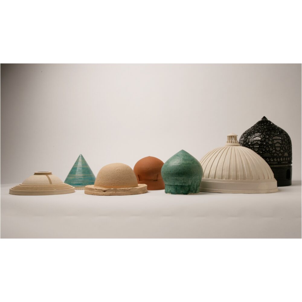 Display of various ceramic dome and cone sculptures in muted earth tones resting on a flat surface by Shahpour Pouyan. (Alt-text generated by AI)