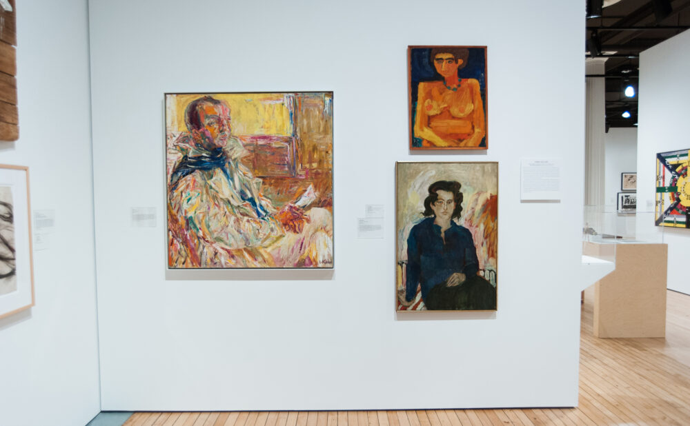 Gallery corner hung with framed figurative portraits and expressive oil paintings. (Alt-text generated by AI)