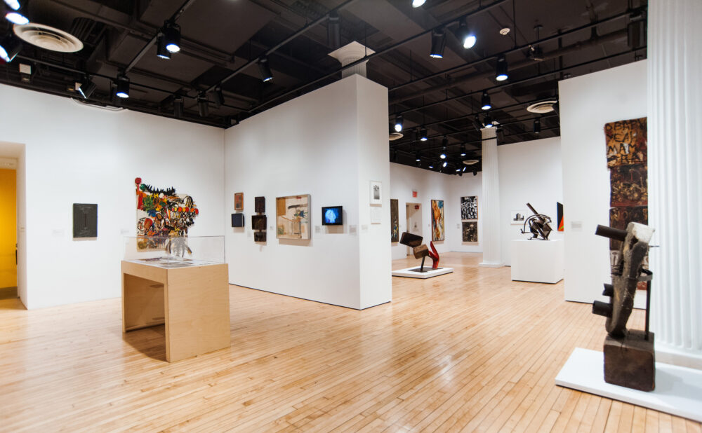 Wide perspective of the exhibition space showcasing various free-standing sculptures, assemblage works, and partition walls. (Alt-text generated by AI)
