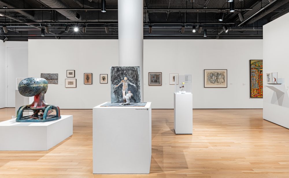 An art gallery with sculptures on pedestals and framed artworks on the walls.