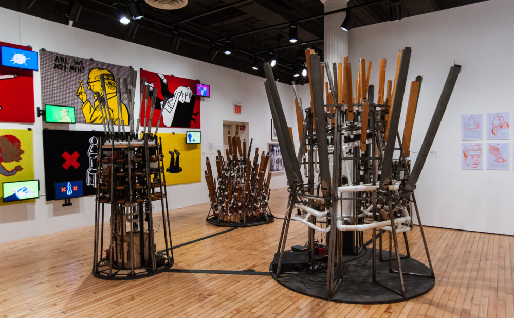 Gallery room displaying metallic, cage-like organ and musical instrument sculptures mounted on circular bases. (Alt-text generated by AI)