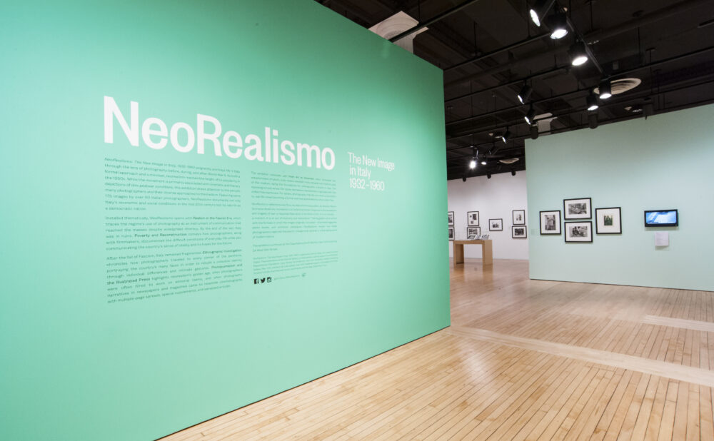 Entry wall featuring a large mint-green backdrop with the exhibition title "NeoRealismo" in white lettering. (Alt-text generated by AI)