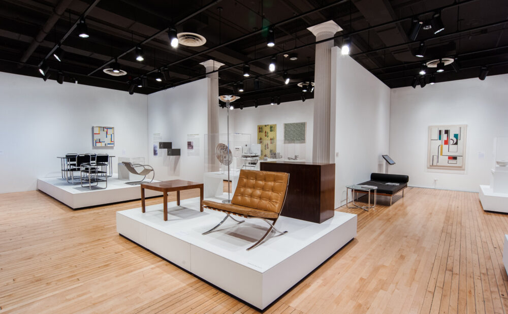 High-angle view of the exhibition floor showcasing multiple furniture platforms arranged across the hardwood gallery space. (Alt-text generated by AI)