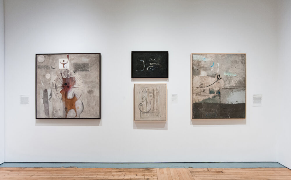 Art gallery wall with four abstract paintings of different sizes and compositions.
