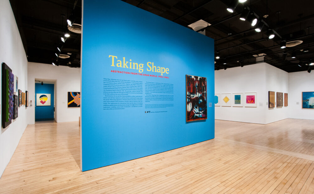 Art gallery with an exhibit titled "Taking Shape: Abstraction from the Arab World, 1950s-1980s" on a prominent blue wall.