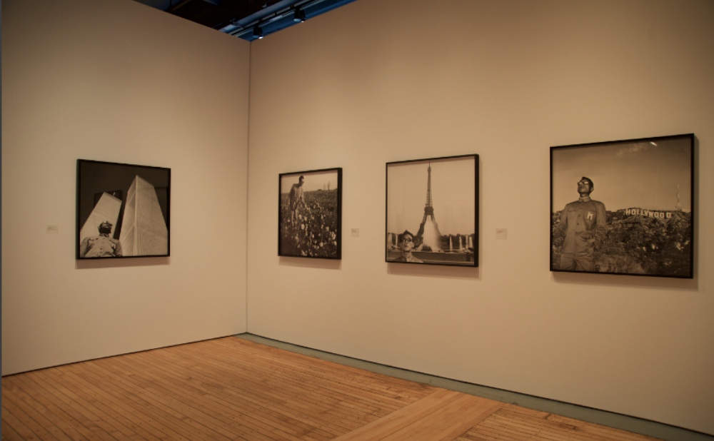 Corner exhibition space featuring a framed photographic series on white walls. (Alt-text generated by AI)
