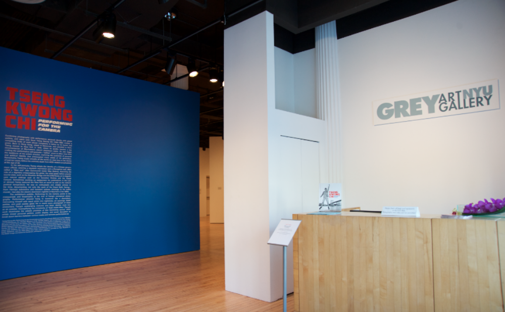 Exhibition entry view featuring the gallery front desk and a bright cobalt blue entry wall with the title "TSENG KWONG CHI" in red text.