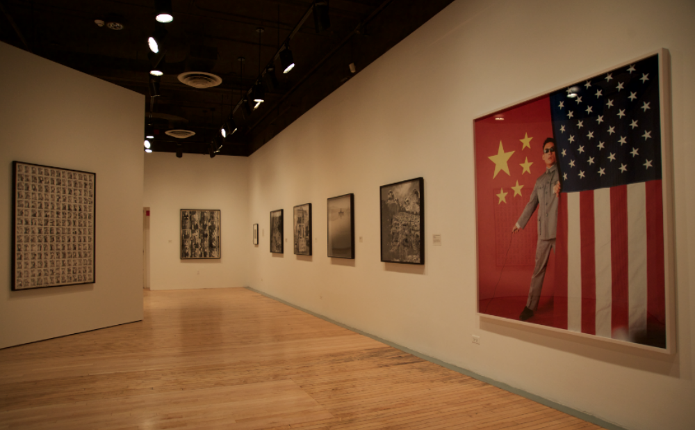 Gallery hallway view featuring a framed photographic series on white walls. (Alt-text generated by AI)