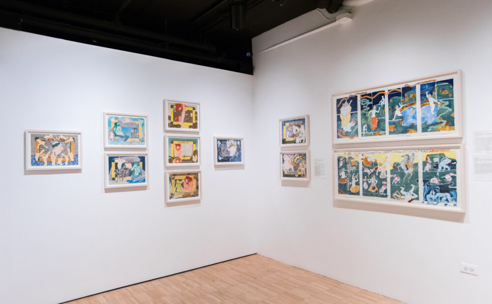 Gallery corner displaying groups of framed artwork under overhead track lighting. (Alt-text generated by AI)
