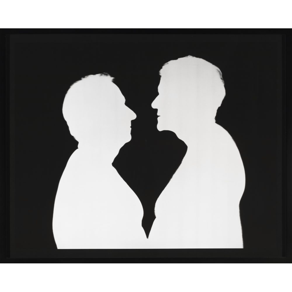 Two men face each other in stark silhouette. The men are white and the background is black. The contrast is sharp like a Victorian silhouette and flattens the figures, who are close enough that their possibly bare bellies possibly touch.