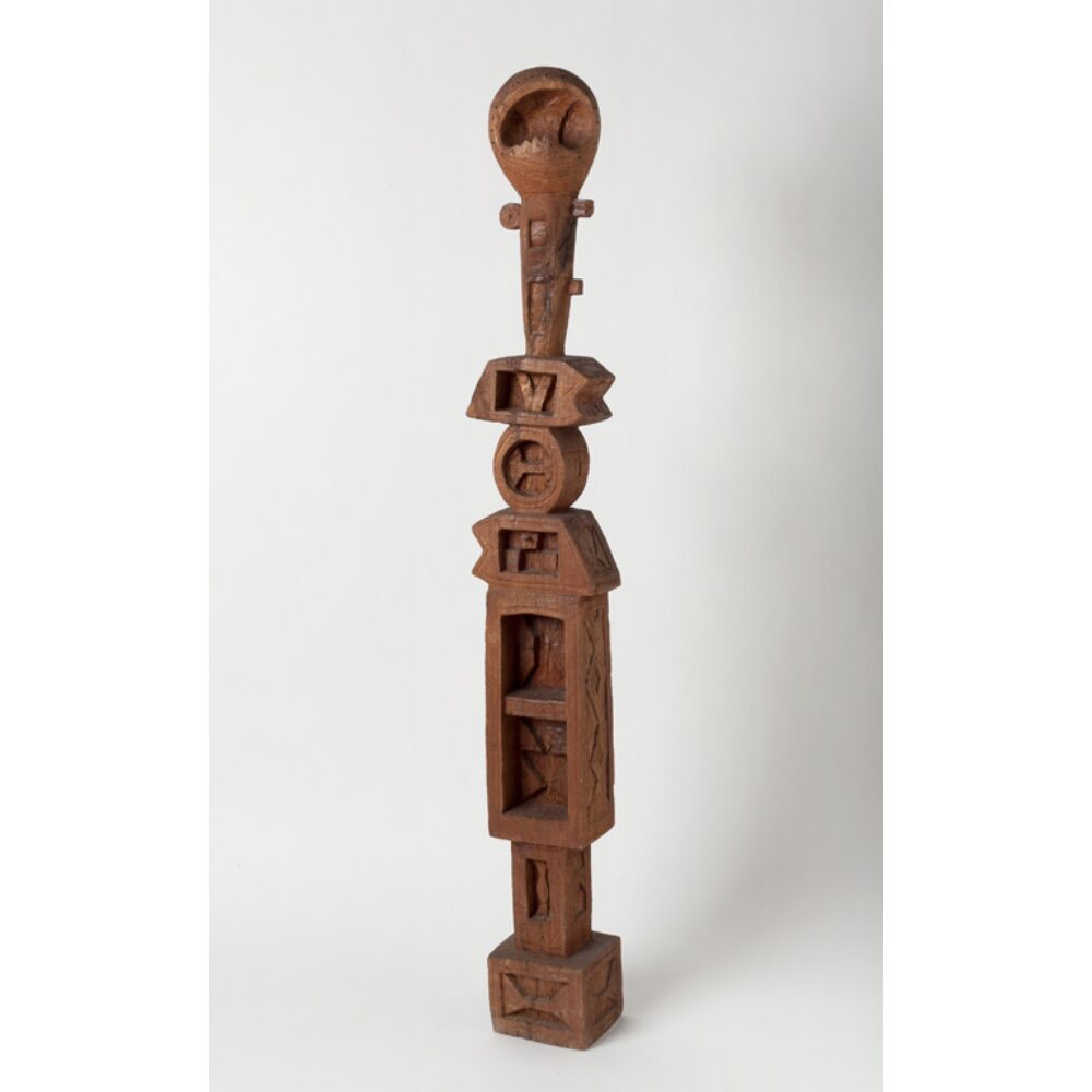 A tall brown sculpture with geometric shapes and carvings. Alt-text generated by AI.