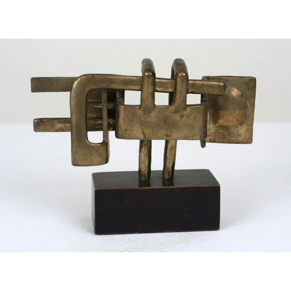 Bronze sculpture consisting of interconnected shapes, including rectangular and elongated forms, suggesting a complex, woven structure. The sculpture is on a wooden rectangular base.
