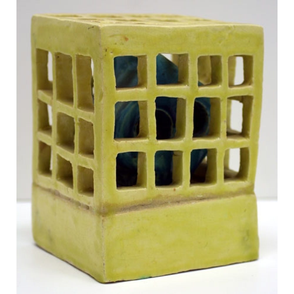 A yellow ceramic cube with square openings and a blue abstract Persian calligraphic heech form inside.