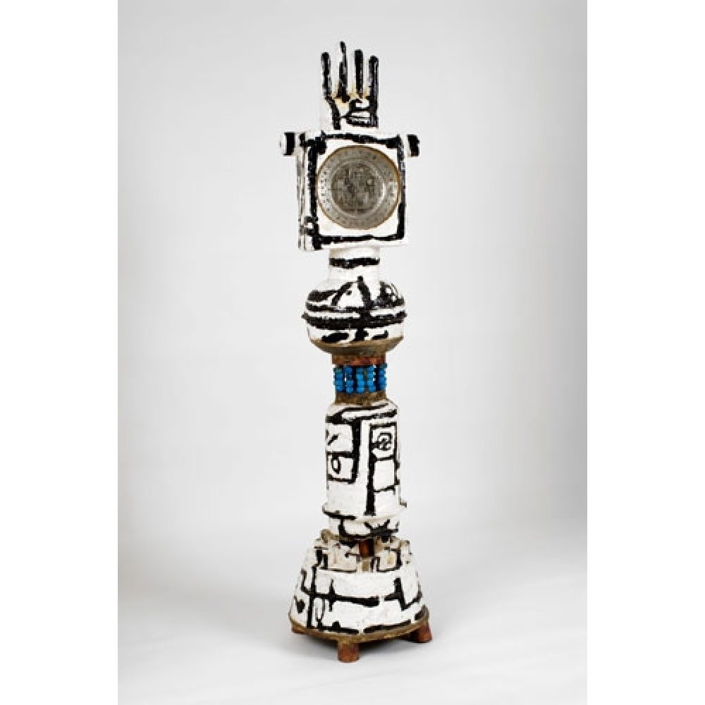 Tall sculptural artwork with geometric black patterns on a white base, topped by a hand motif.