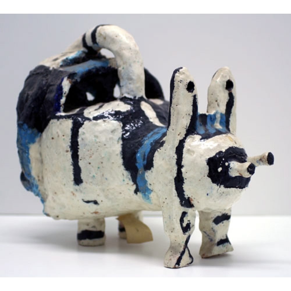 Abstract ceramic sculpture resembling a four-legged creature with pointed ears and a long tail, in white, black, and blue hues.