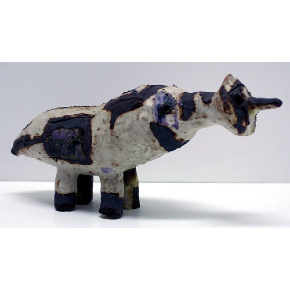 Abstract ceramic sculpture resembling a four-legged creature with dark patches on a light ground.