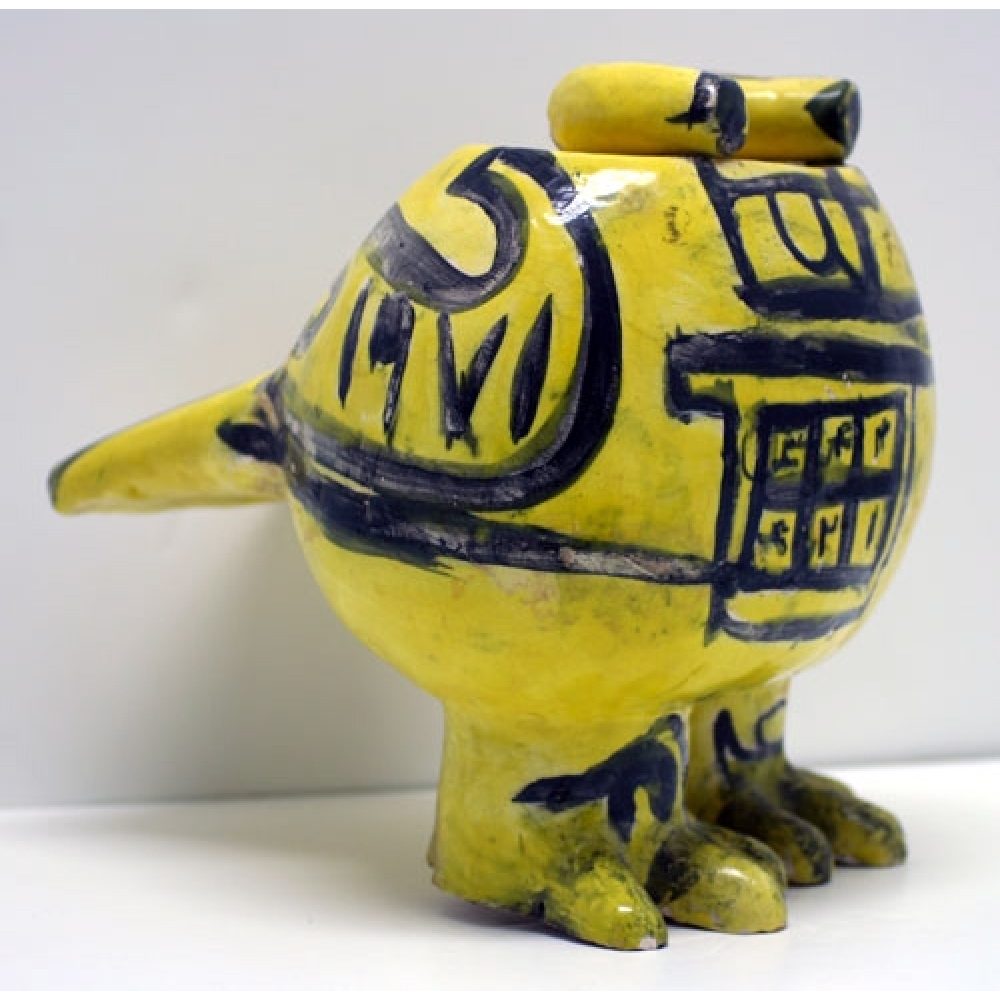Yellow ceramic sculpture in the abstracted form of a bird, with black accents.