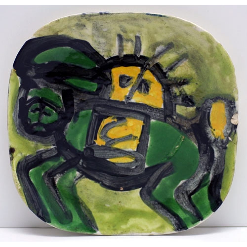 Ceramic plate with abstract green, yellow, and black design, possibly depicting an animal.