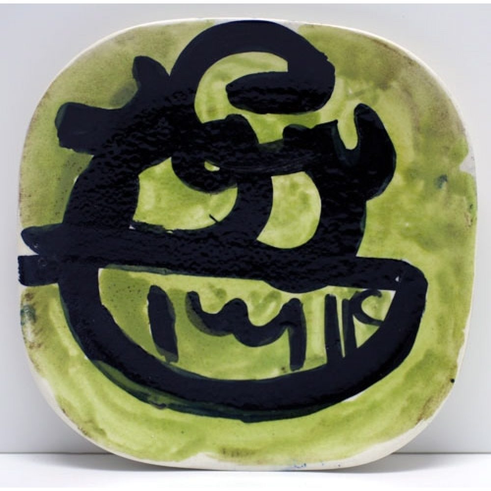 Ceramic plate with green background and bold black abstract design.
