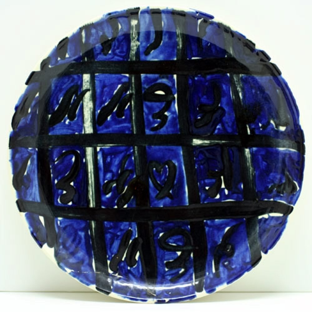 Ceramic plate with blue and black abstract design featuring grid pattern and symbols.