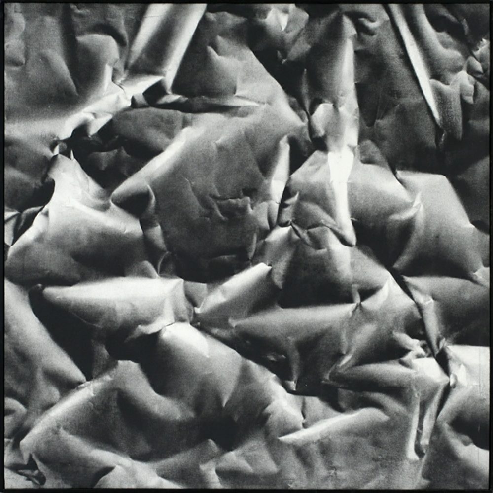 Monochrome artwork composed of a concentrated arrangement of folds and creases, with the painted shapes forming a crumpled paper texture.