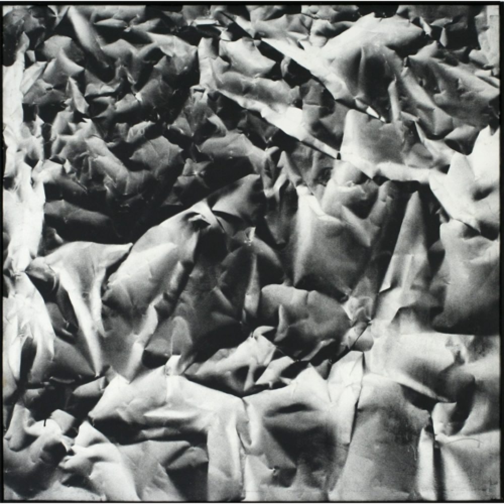 Monochrome artwork composed of a concentrated arrangement of folds and creases, with the painted shapes forming a crumpled paper texture.