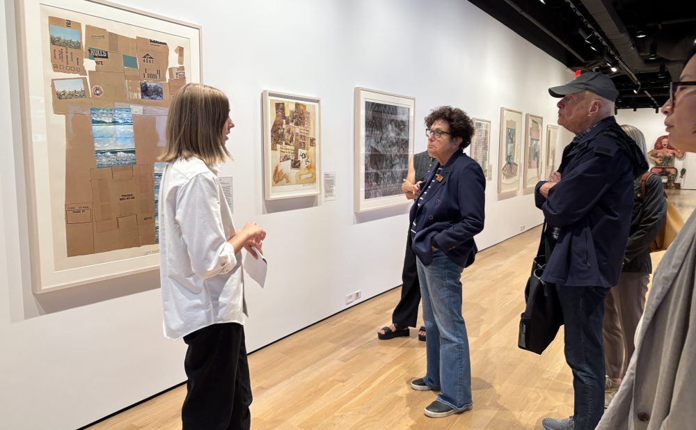 People observing art on a gallery wall.  Alt-text generated by AI.