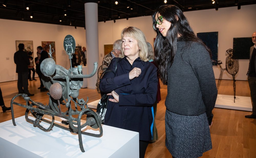 Two people viewing a metal sculpture in an art gallery.