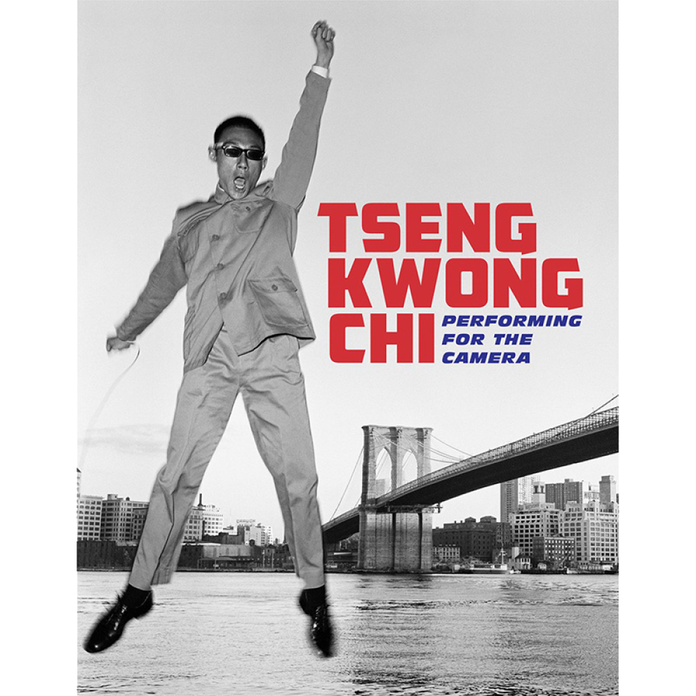Book cover showing a photograph of a man in a suit jumps with one arm raised, with the Brooklyn Bridge and cityscape in the background. Text reads "Tseng Kwong Chi: Performing for the Camera."