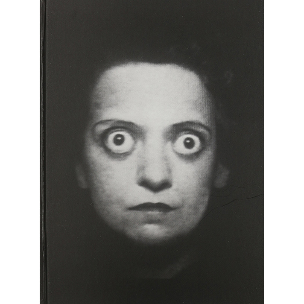 Close-up black and white photo of a woman's face with wide eyes on a book cover.