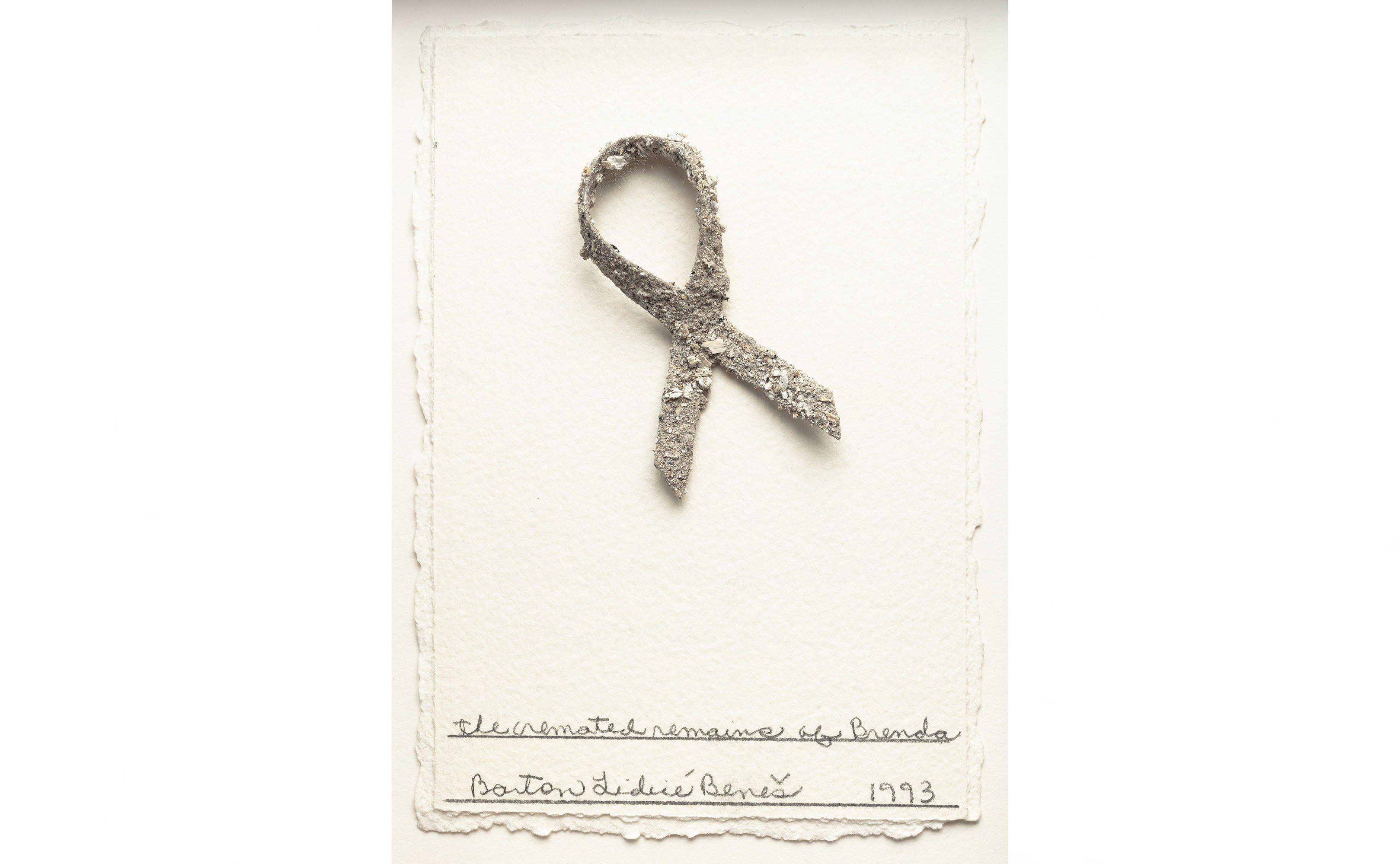 A ribbon shape made from granular material on textured paper with handwritten text below.